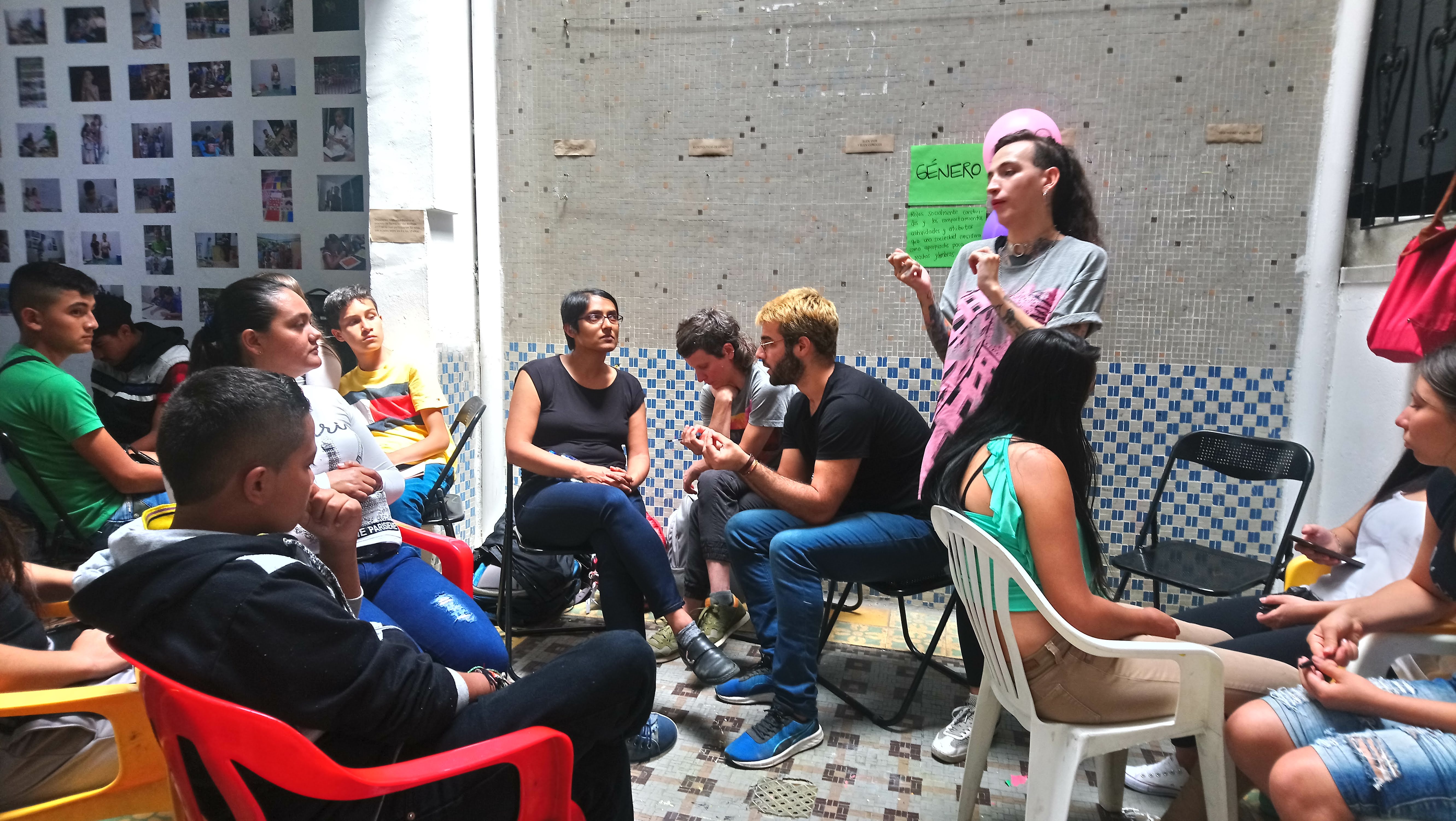 A group of people is listening to a person that is talking to them. The groups is sat and look calm.